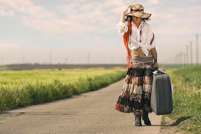 mulher-andando-pela-estrada-com-mala-na-m-c3-a3o